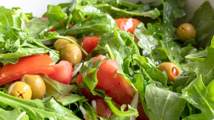 TORONTO, ONTARIO, CANADA – 2019/07/30: Arugula salad. The vegetarian food is mixed with pieces of tomatoes and olives. Healthy food green salad.