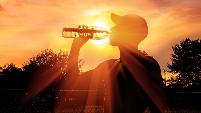 Silhouette of a man drinking water during heat wave