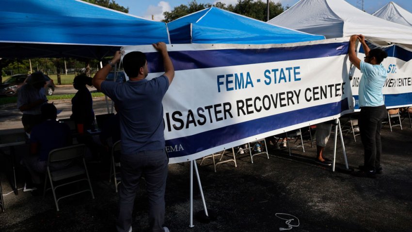 FEMA employees Alec Villeneuve, left, and Thomas Yahn hang a banner on Friday, May 12, 2023, at a FEMA Disaster Recovery Center in Hollywood, Florida. The Federal Emergency Management Agency helps prepare for, respond to and recover from emergencies. A proposed law would separate FEMA from the Department of Homeland Security. (Amy Beth Bennett/South Florida Sun Sentinel/Tribune News Service via Getty Images)