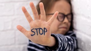 Una niña muestra su mano con la inscripción STOP.