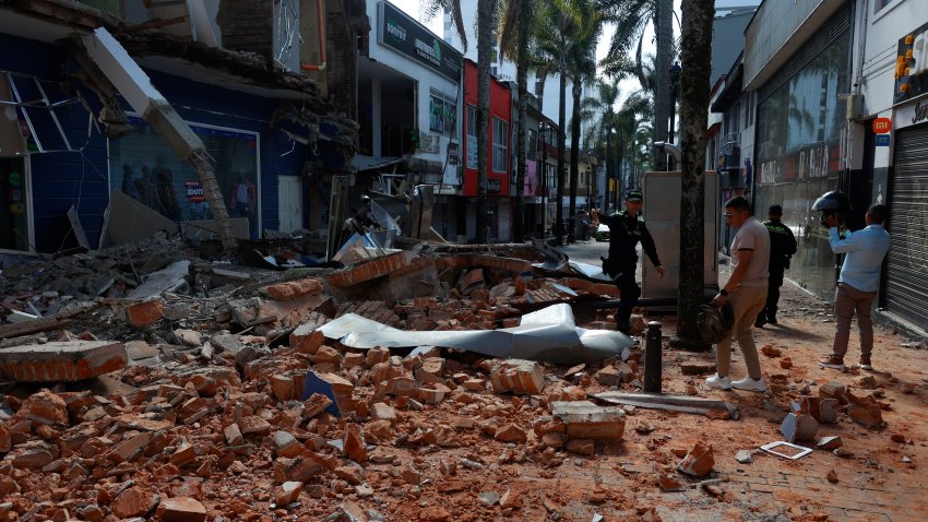 Personas caminan frente a una edificación afectada tras un fuerte temblor este lunes, en Manizales (Colombia).